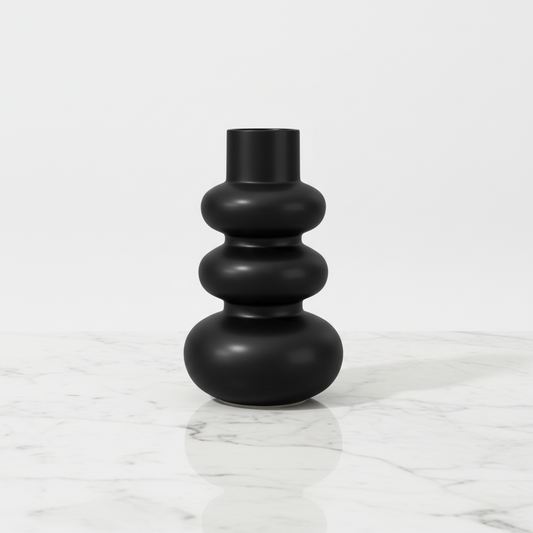 Close-up of matte black ripple curvy ceramic vase on marble surface